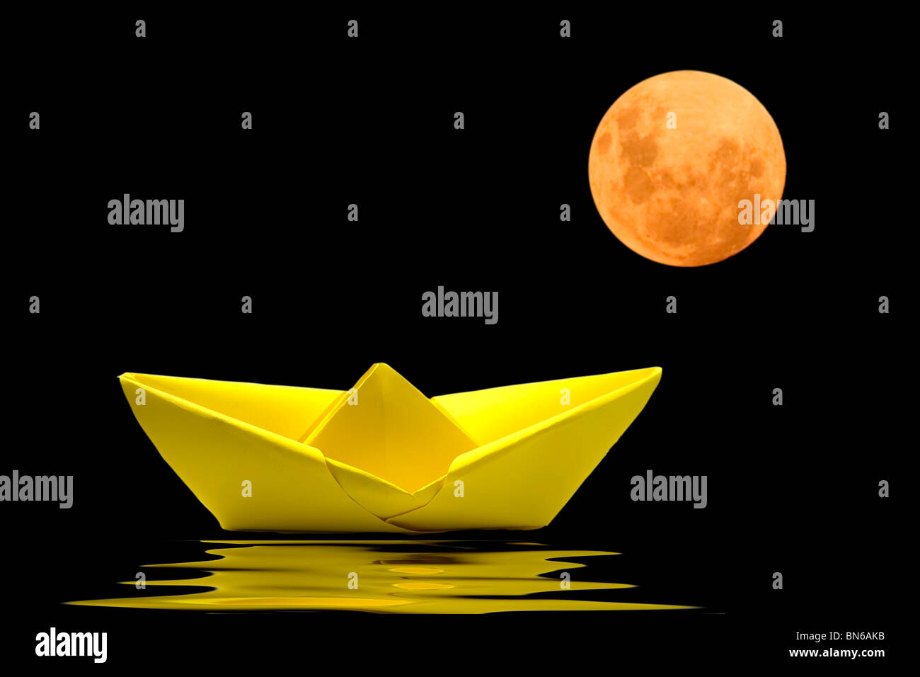 Gelbes Papierboot auf dem Wasser mit verschwommenen Mond hinter Stockfoto