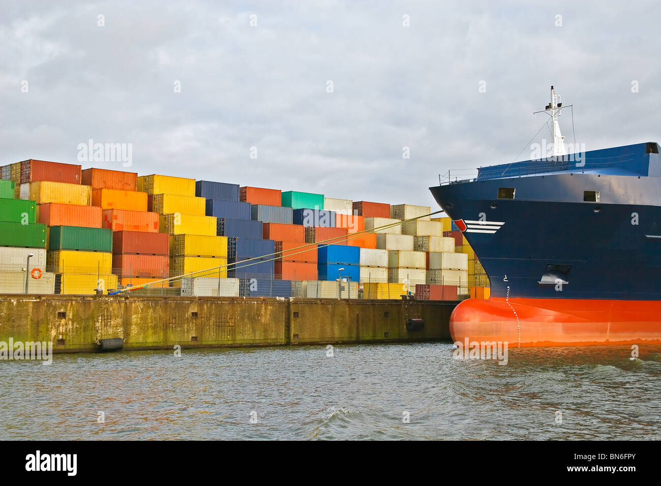 Cargo Container gestapelt am Hafen-Terminal mit großen Containerschiff Stockfoto