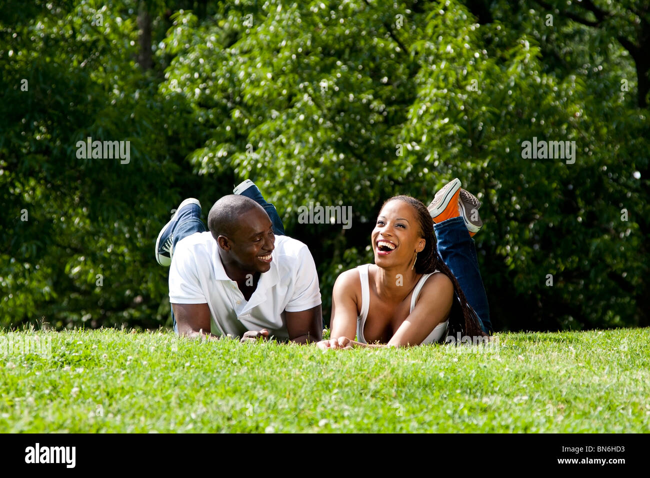 Schöner Spaß glücklich lächelnd, lachend, afrikanischen amerikanischen Ehepaar Scherz Verlegung auf dem Rasen im Park. Stockfoto