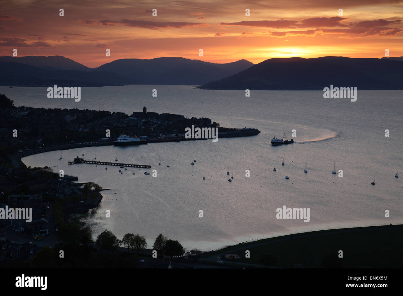 Sonnenuntergang über der Stadt Gourock und dem Firth of Clyde mit einer Calmac Fähre nähert sich, Inverclyde, Westküste von Schottland, Großbritannien Stockfoto