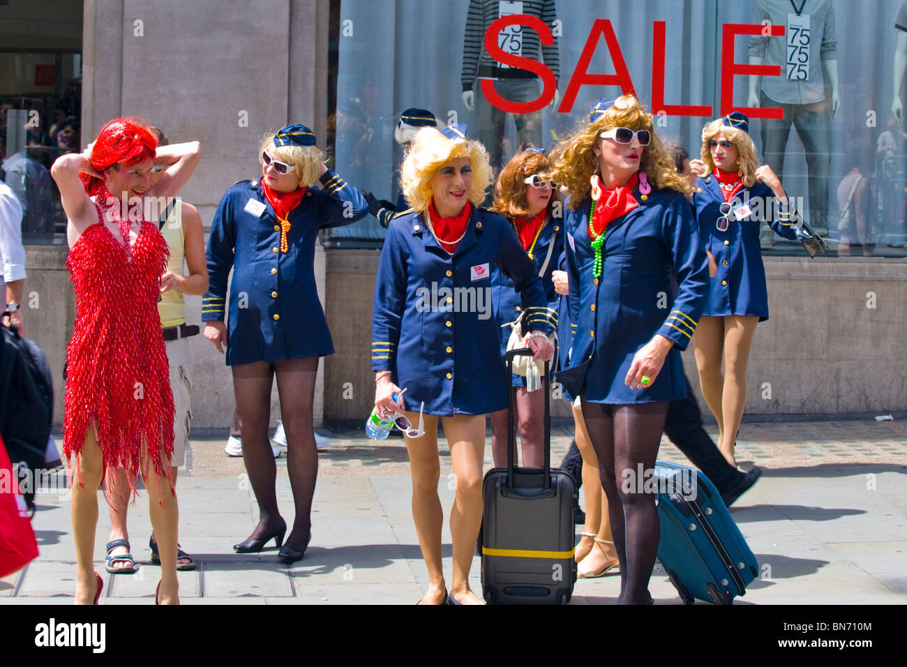 London Gay Pride, junge Männer gekleidet als Stewardessen in kurzen  Kleidern, weiblichen Perücken, Highheels & Strumpfhosen machen Sie sich  bereit für Festzug Stockfotografie - Alamy