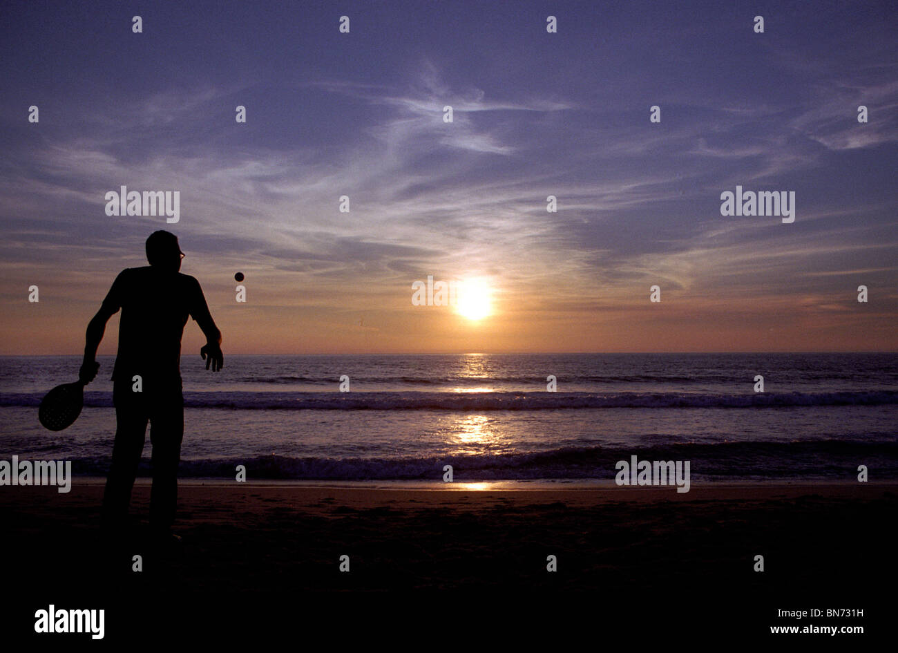 Mann, der Schläger am Strand spielt Stockfoto