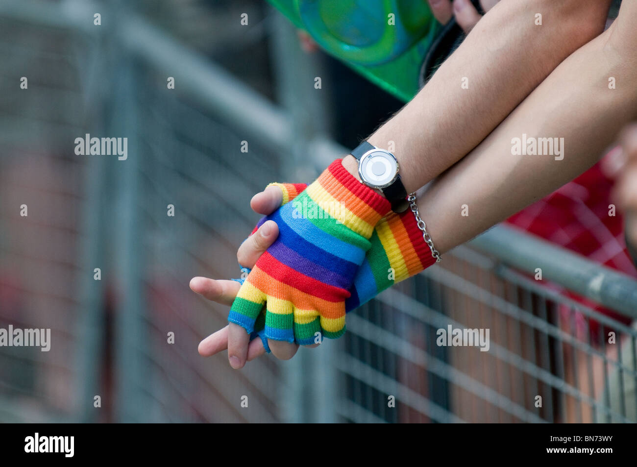Bunte fingerlose Handschuhe getragen von zwei schwule bei den London Pride Feierlichkeiten in London. Stockfoto