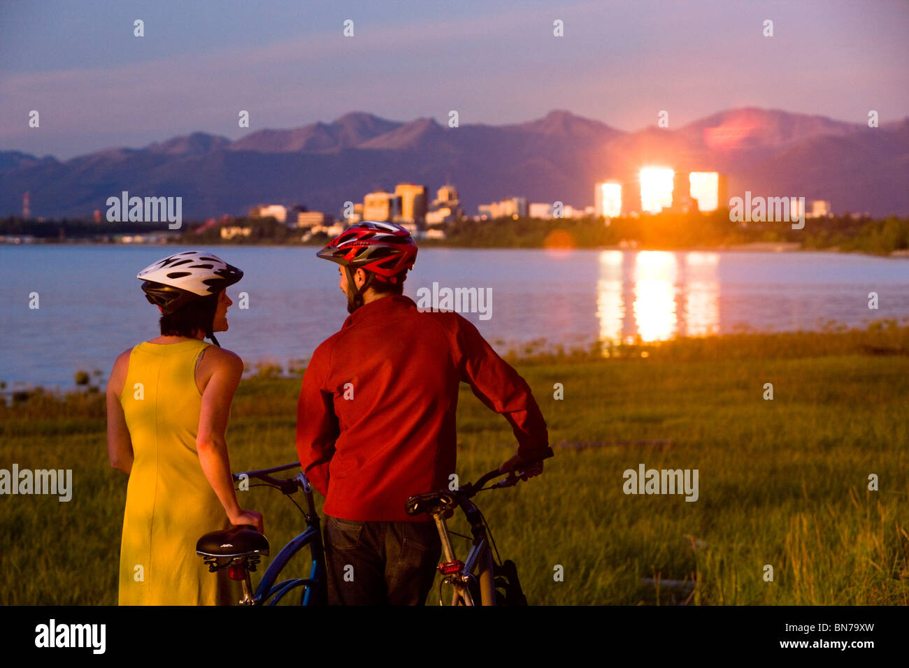 Radfahrer-Reste und und genießt den Sonnenuntergang entlang der Tony Knowles Coastal Trail mit der Verankerung im Hintergrund, Alaska Stockfoto