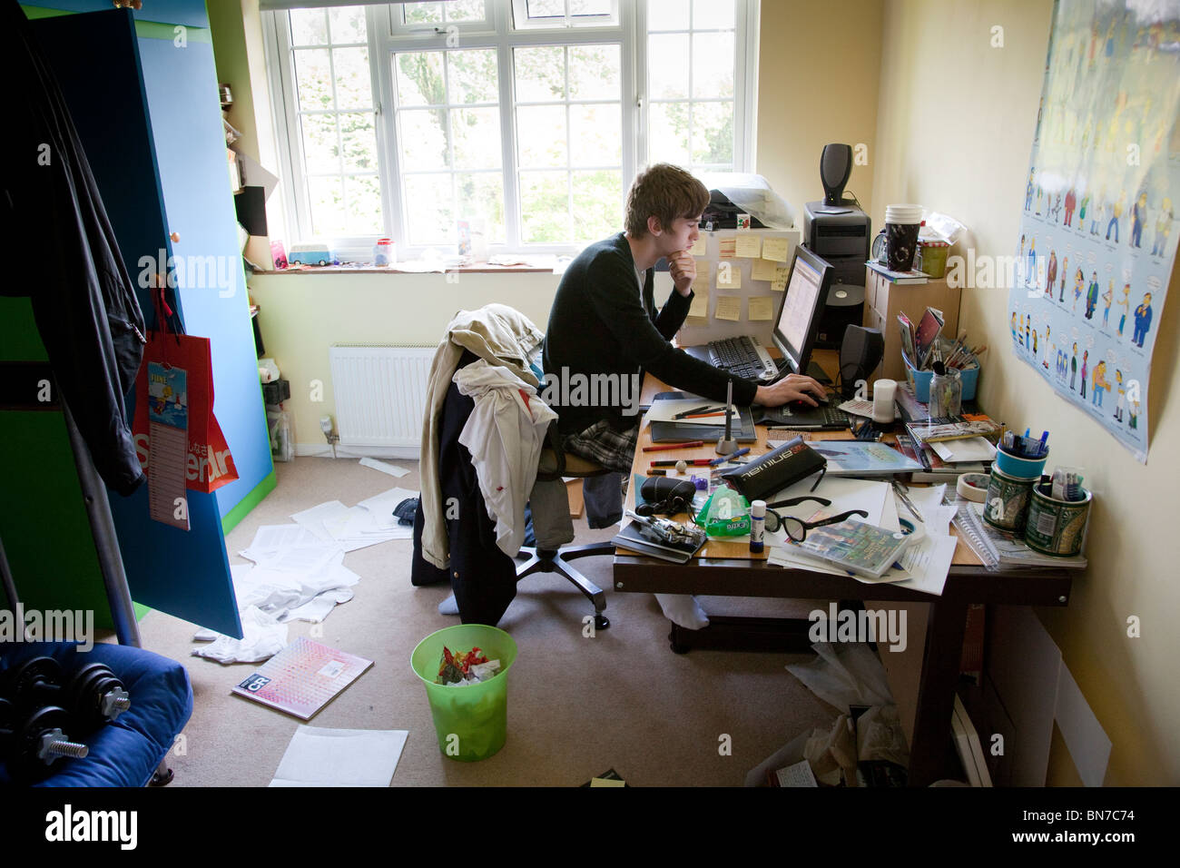 Teenager, die an einem Computer in einem unordentlichen Zimmer studieren. Stockfoto