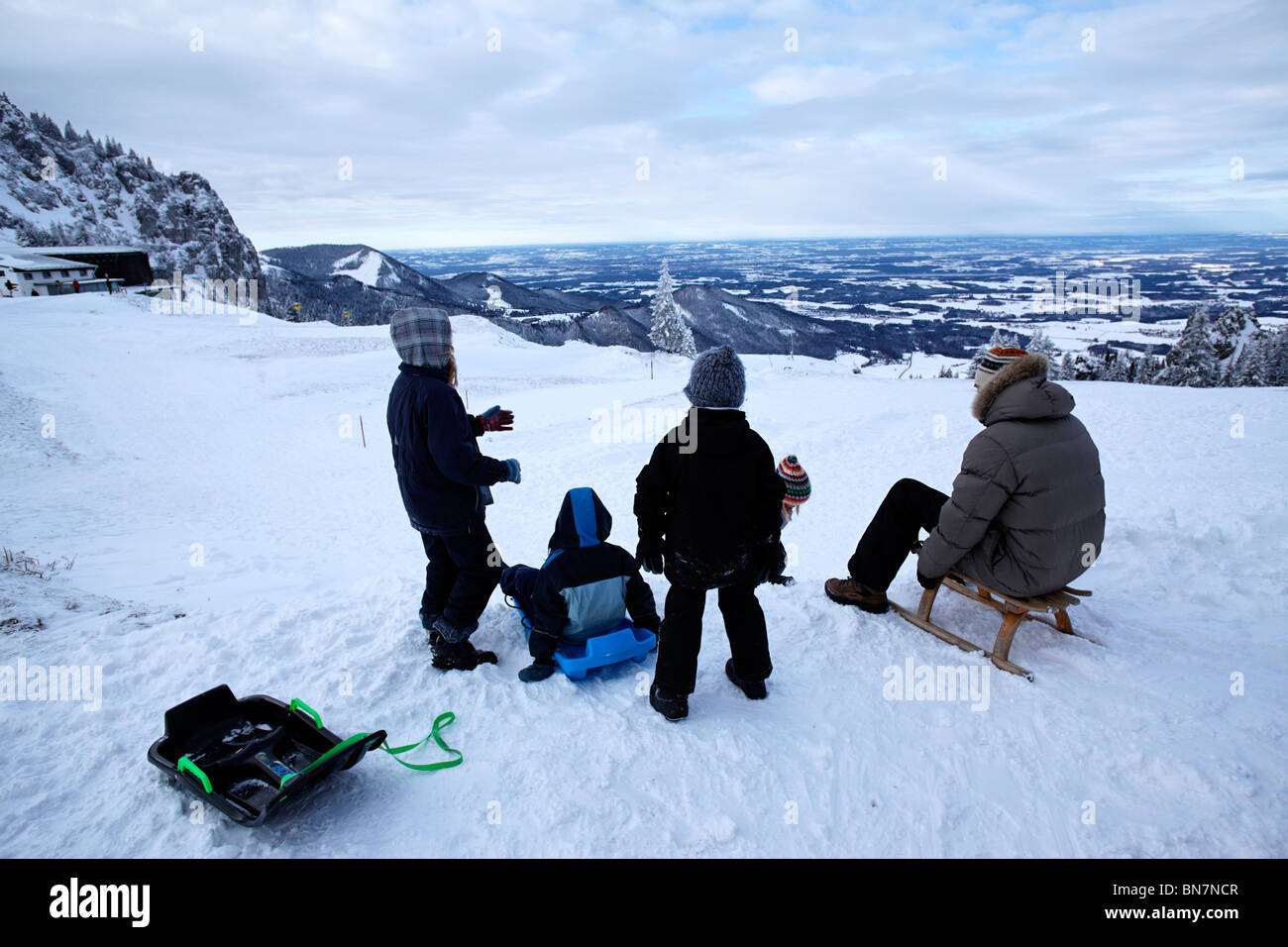 Familie auf dem Schneeschlitten die Kampenwand oberen Bayern Chiemgau Stockfoto