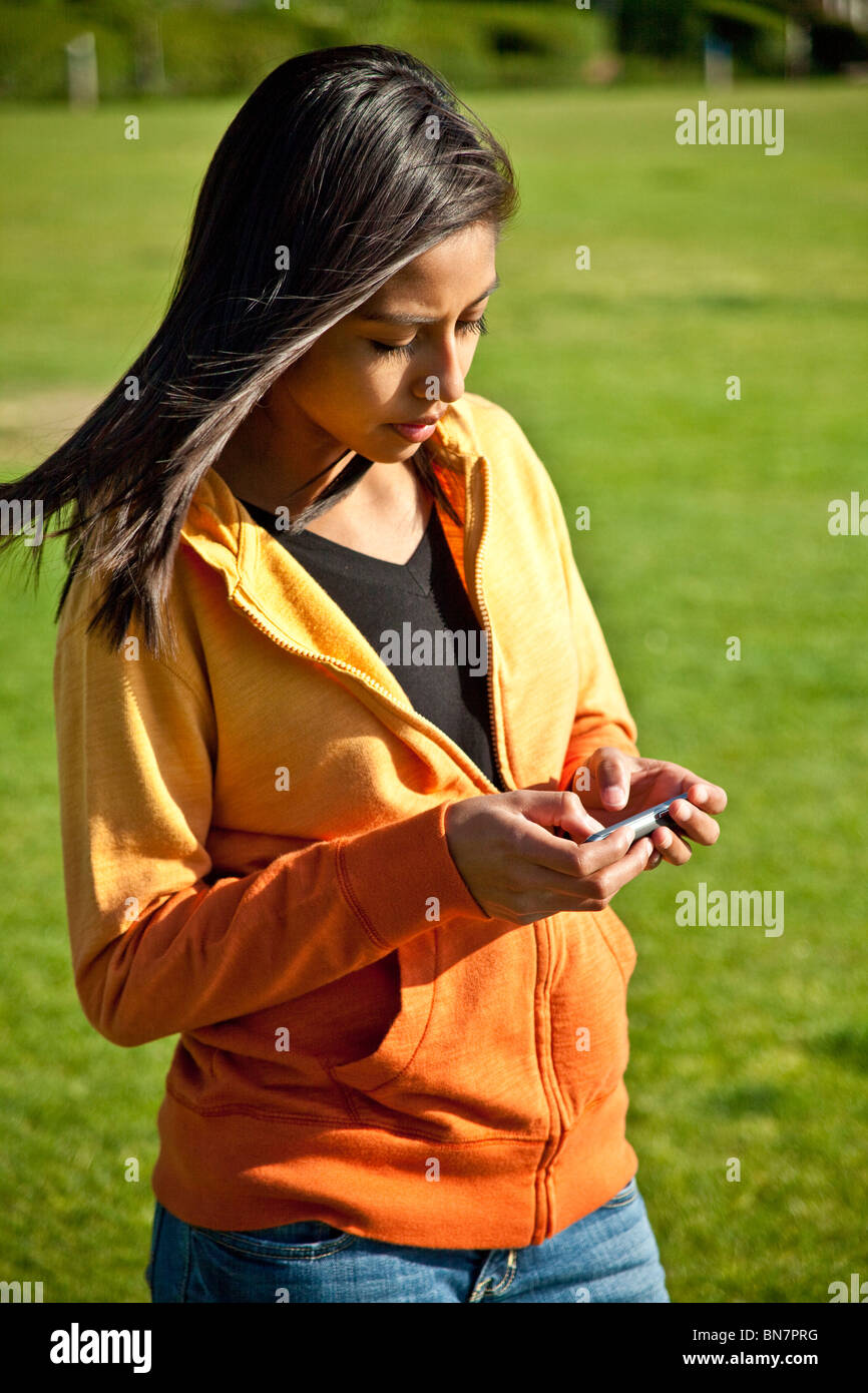 16 Jahre Jahre alt hispano-amerikanischen Mädchen SMS mit iPhone Mobile Phone. Herr © Myrleen Pearson Stockfoto
