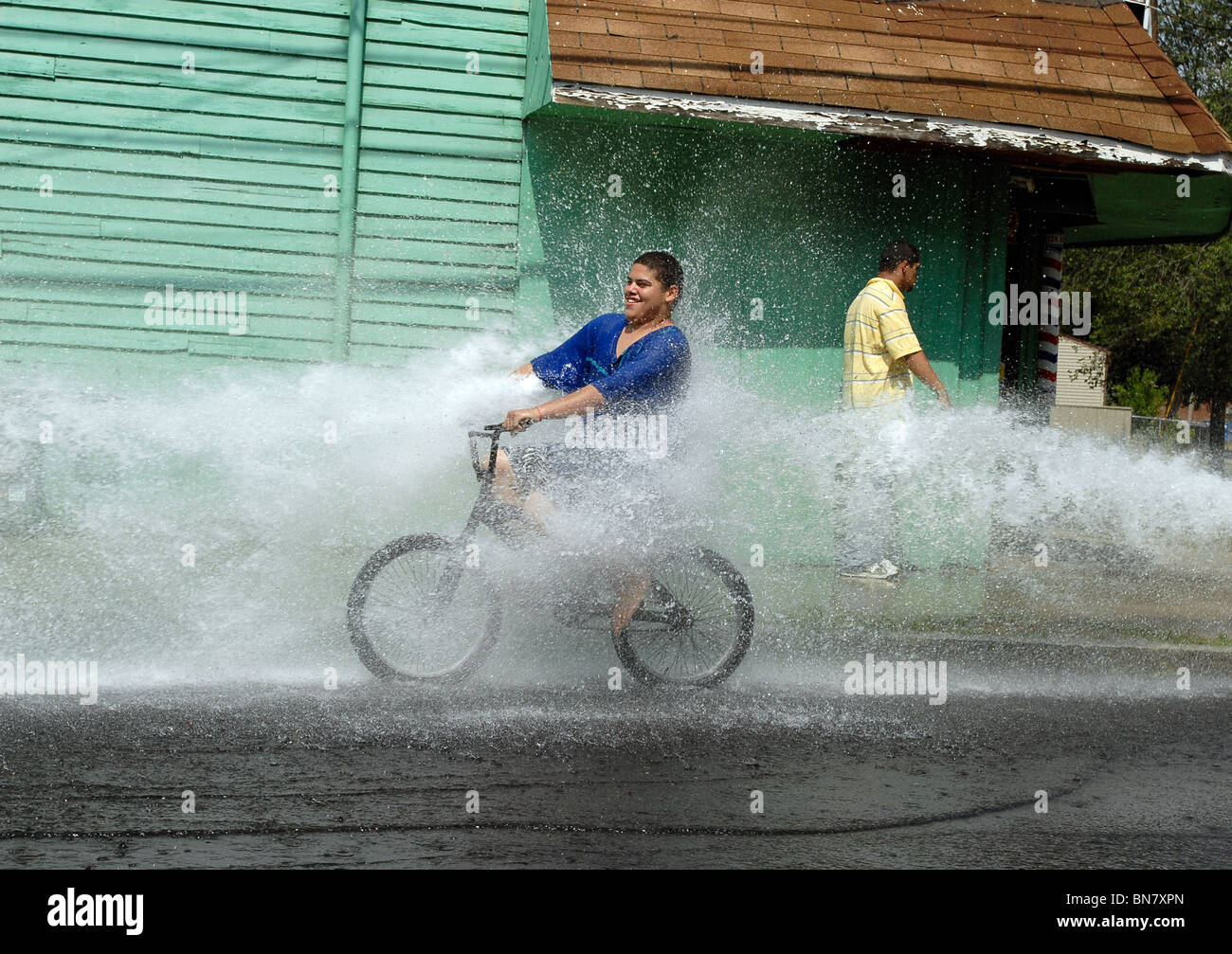 Eine junge Teen reitet durch das Spray von einer offenen Hydranten während einer Hitzewelle in New Haven CT USA wo Temps über 100 F waren. Stockfoto