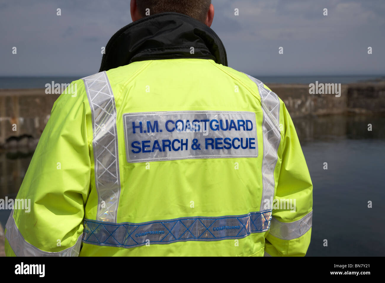 HM Coastguard Suche und Rettung Personal tragen Hivis Jacke gerade nahe dem Meer in Großbritannien Stockfoto