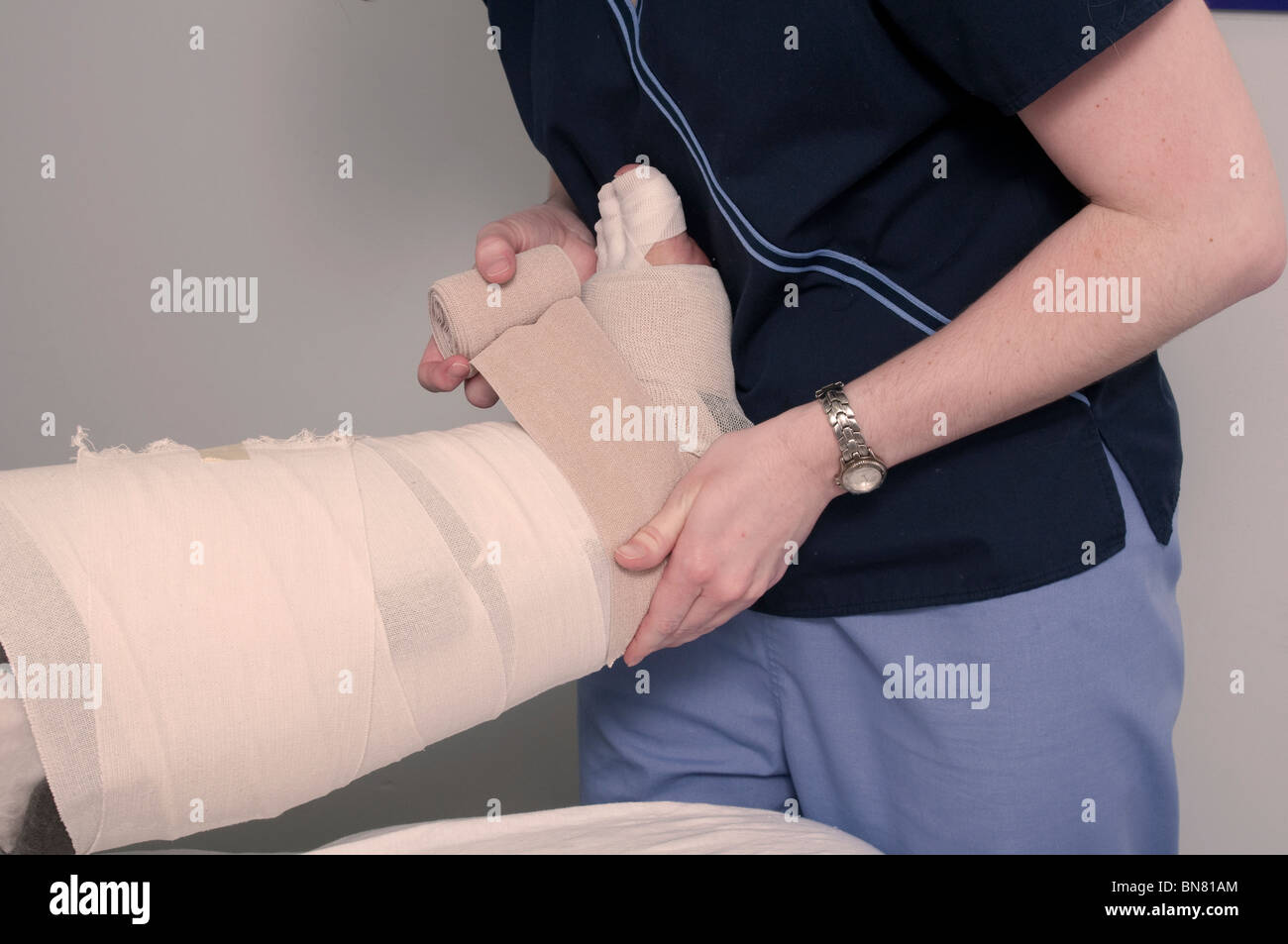 Physiotherapeut Verpackung Bandage um das Bein einer Patientin Stockfoto