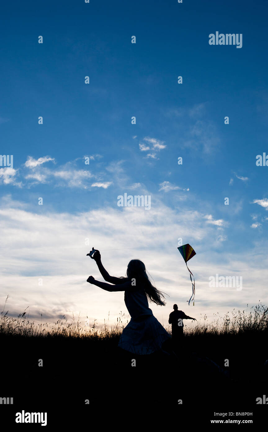 Junge Mädchen und Erwachsene Spaß ein Drachen in der englischen Landschaft. Silhouette Stockfoto