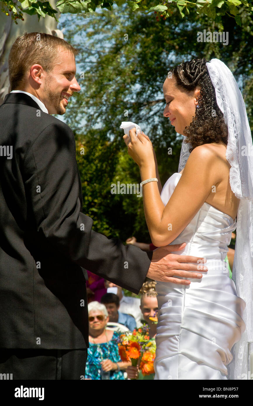 Eine gemischtrassige Braut weint vor Glück bei ihrem formalen im freien Trauung in Orange, CA. Hinweis Bräutigam. Stockfoto