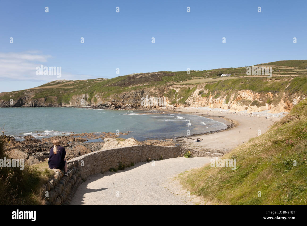 Blick auf einen ruhigen Strand mit mit Leuten im Sommer im Church Bay (Porth Swtan), Isle of Anglesey, North Wales, UK Großbritannien. Stockfoto