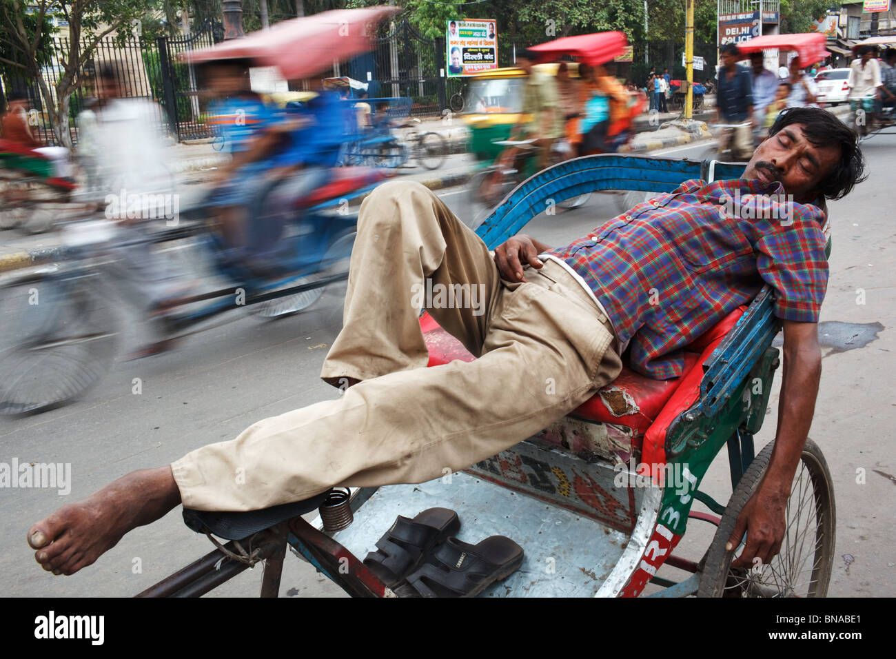 Eine Rikscha Wallah Nickerchen auf seine Rikscha mitten auf der Straße in Chandni Chowk, Alt-Delhi, Indien Stockfoto