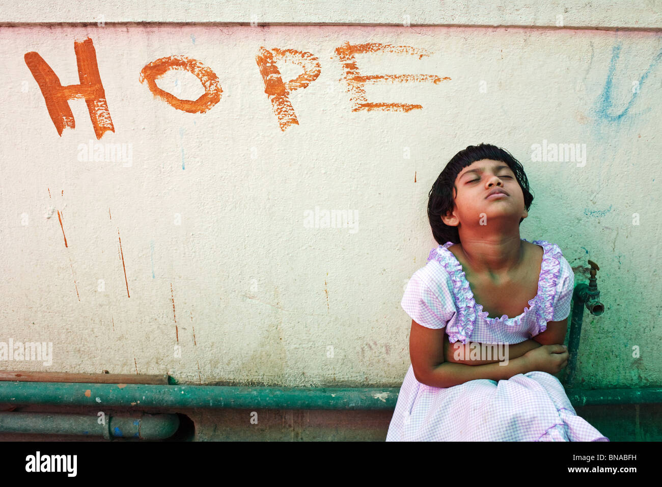 Junges Mädchen sitzt an der Wand mit Hoffnung Schild geschrieben steht in einem Kinderheim für Straßenkinder, ausgeführt von der HOPE-NGO in Kalkutta Stockfoto