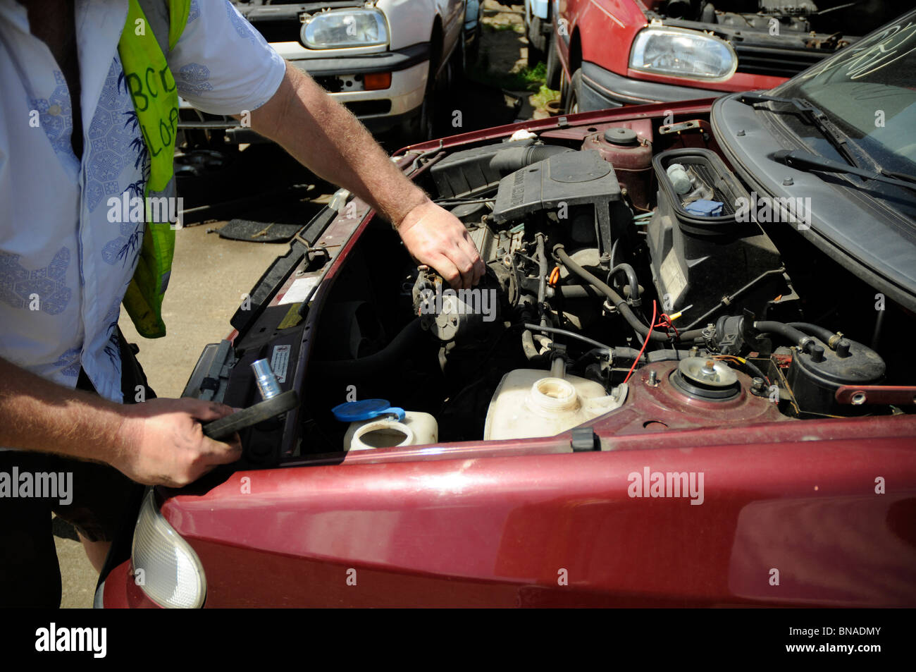 Mann Auto im Breakers Yard ein Anlasser entfernen. Stockfoto