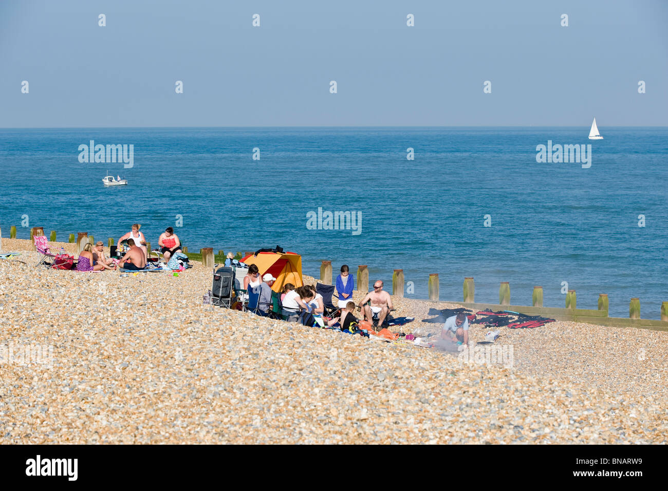Familien genießen Sommersonne am Kiesstrand, Eastbourne, East Sussex, Großbritannien Stockfoto
