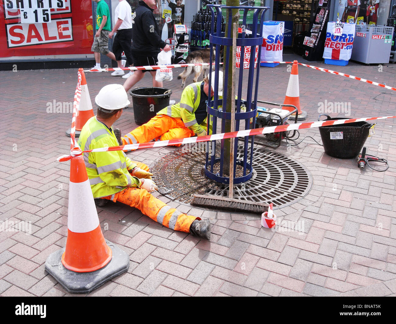 Des Rates Arbeiter ersetzt Kies um Bäume in einer Fußgängerzone Einkaufsviertel Stockfoto