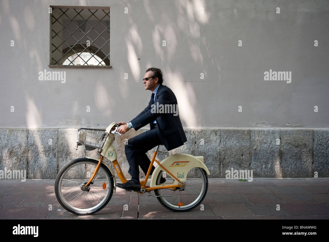 Ein Mann in einem Anzug Reiten ein Fahrrad von BikeMi, die Stadt Bike sharing Service Mailand Italien Stockfoto