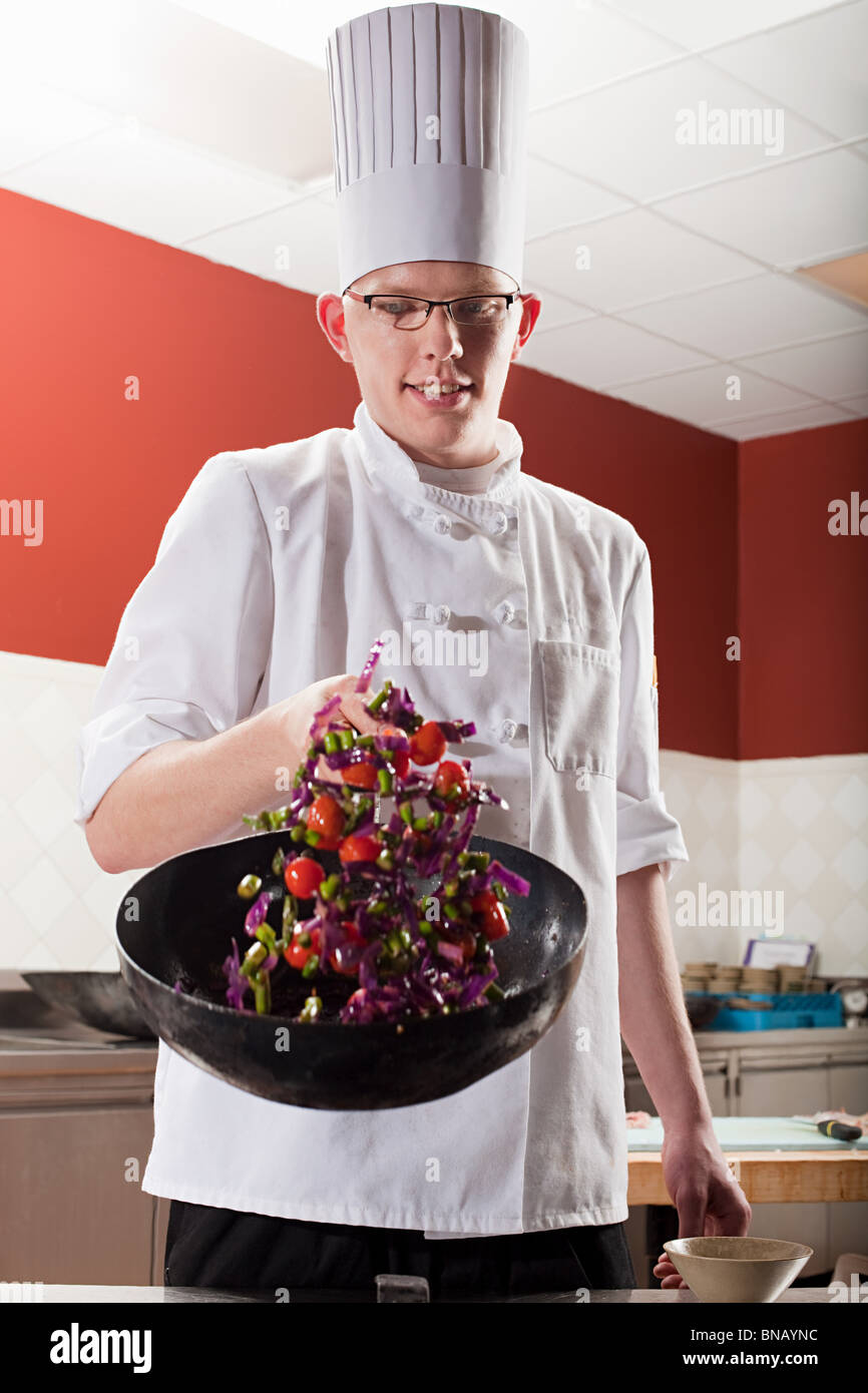 Männliche Koch Braten mit Wok in Großküchen Stockfoto