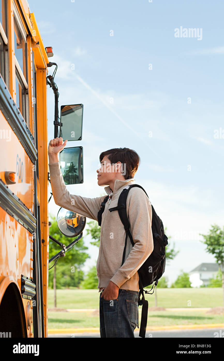 Männlichen High-School-Schüler an Schulbus Tür zu hämmern Stockfoto