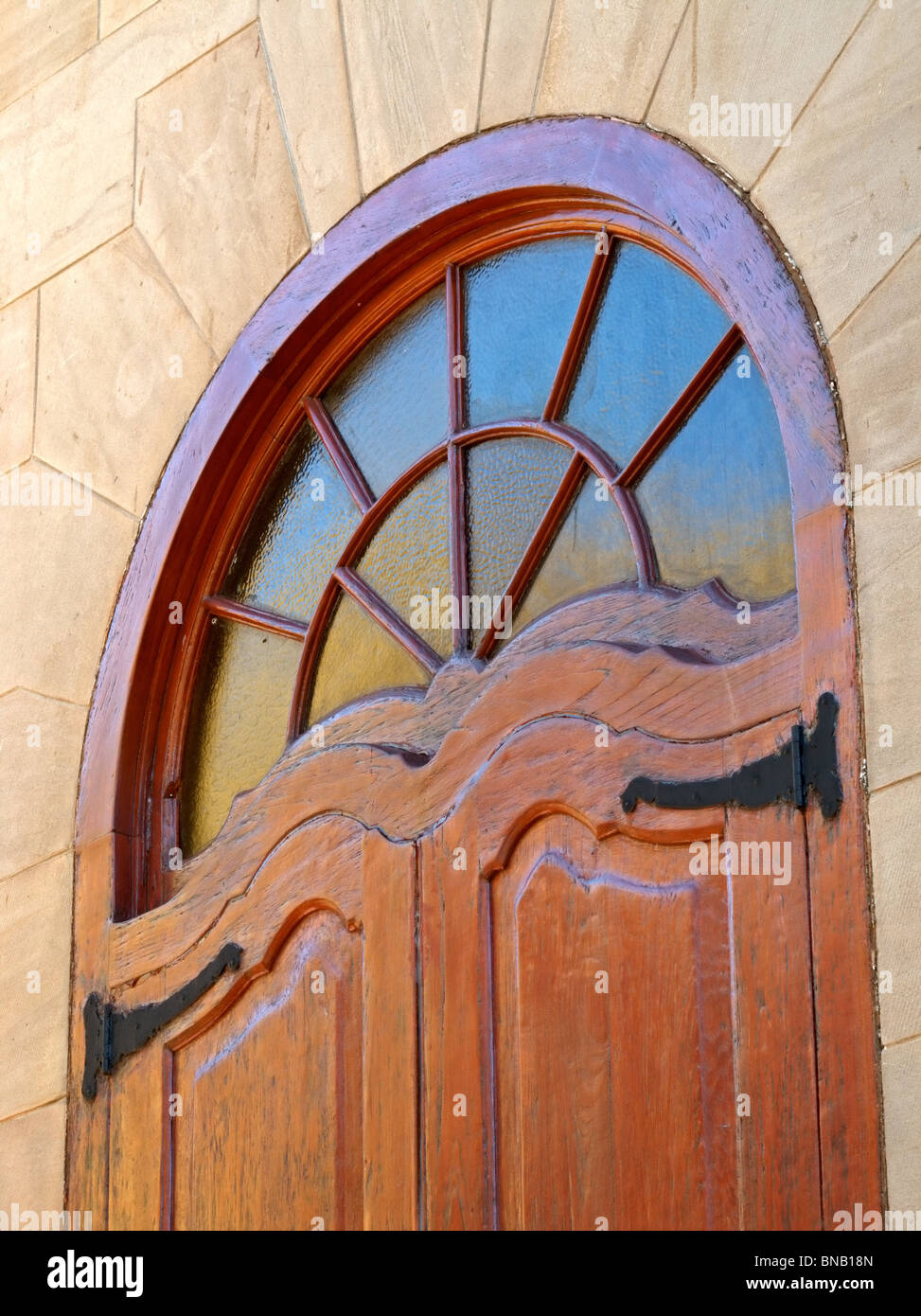 Dekoratives Fenster in einem Holzrahmen mit Sandsteinmauern Stockfoto