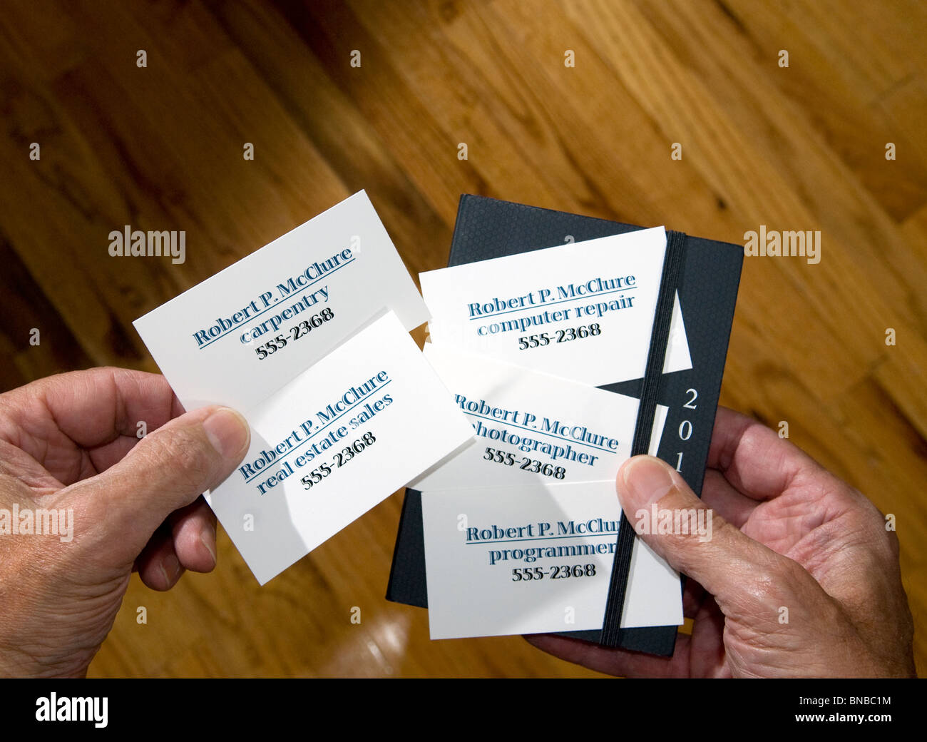 Nahaufnahme der Hände halten mehrere Visitenkarten mit unterschiedlichen berufen Stockfoto