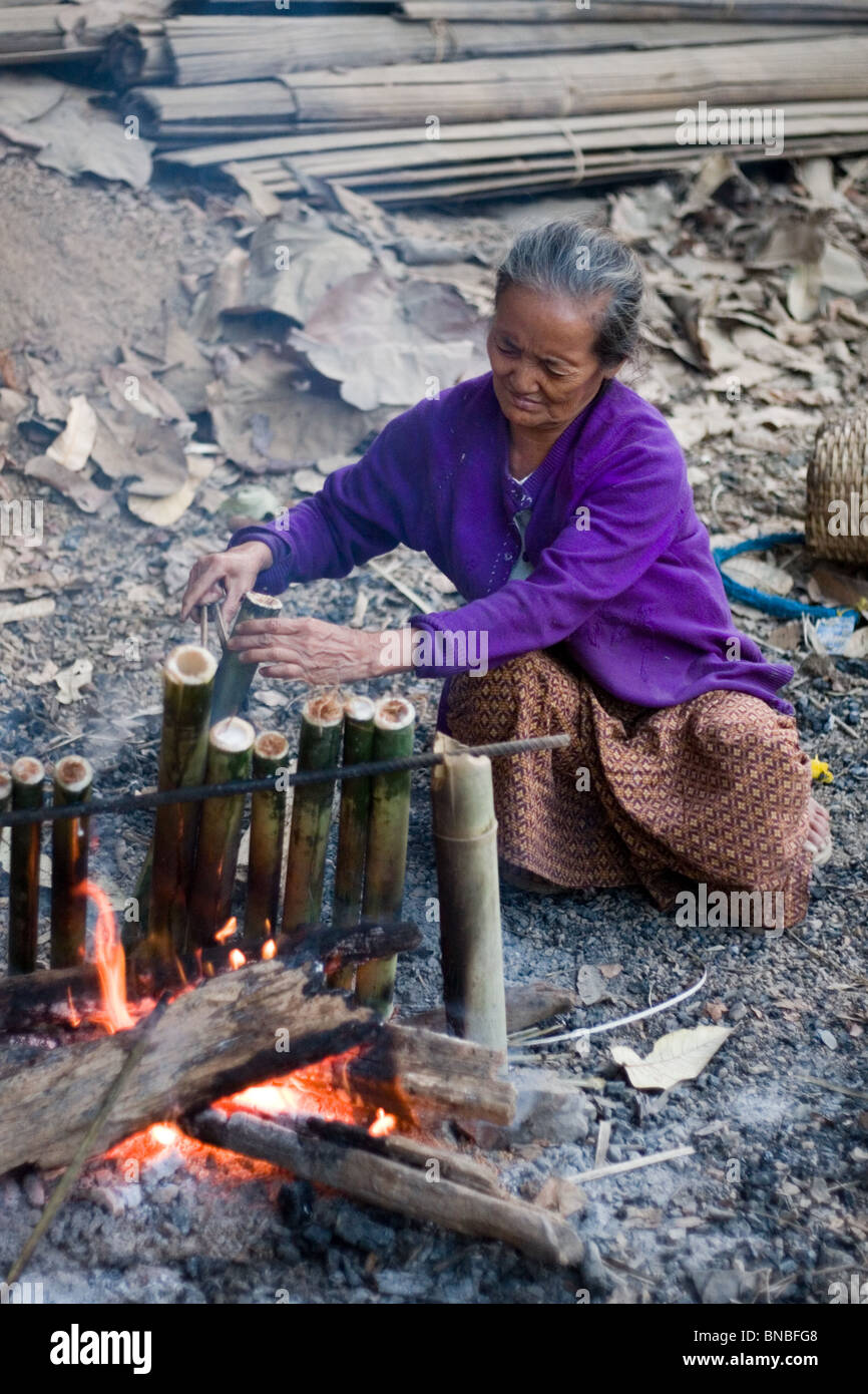 Alte Frau mit Bambus, Kochen über offenem Feuer in Mae Sam Laep, eine burmesische Flüchtlinge Siedlung, Mae Hong Son Provinz, Thailand Stockfoto