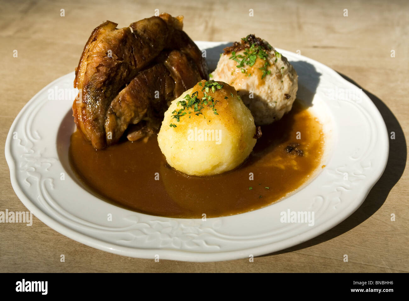 Das traditionelle bayerische Gericht Schweinshaxe (gebratenes Eisbein) serviert mit Kartoffel und Semmelknödel in München. Stockfoto