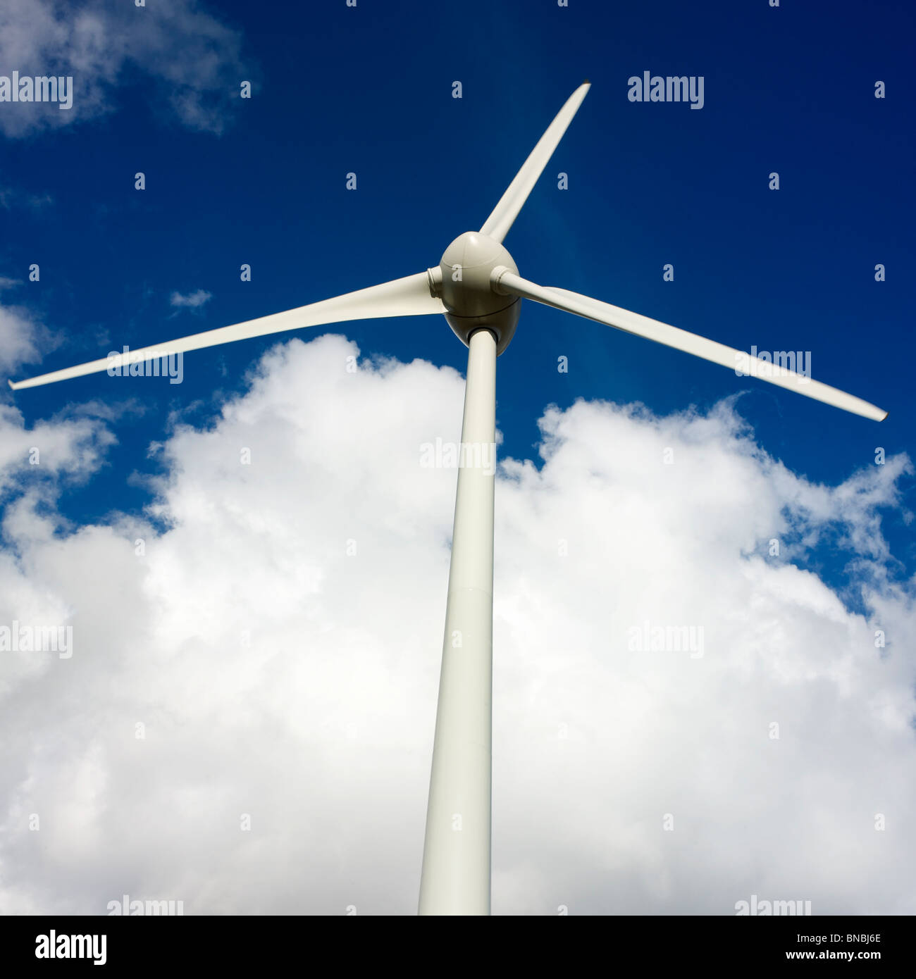 Windenergieanlage am blauen Himmel mit Wolken, die die Erzeugung erneuerbarer Energien in einem ländlichen Gebiet darstellen Stockfoto