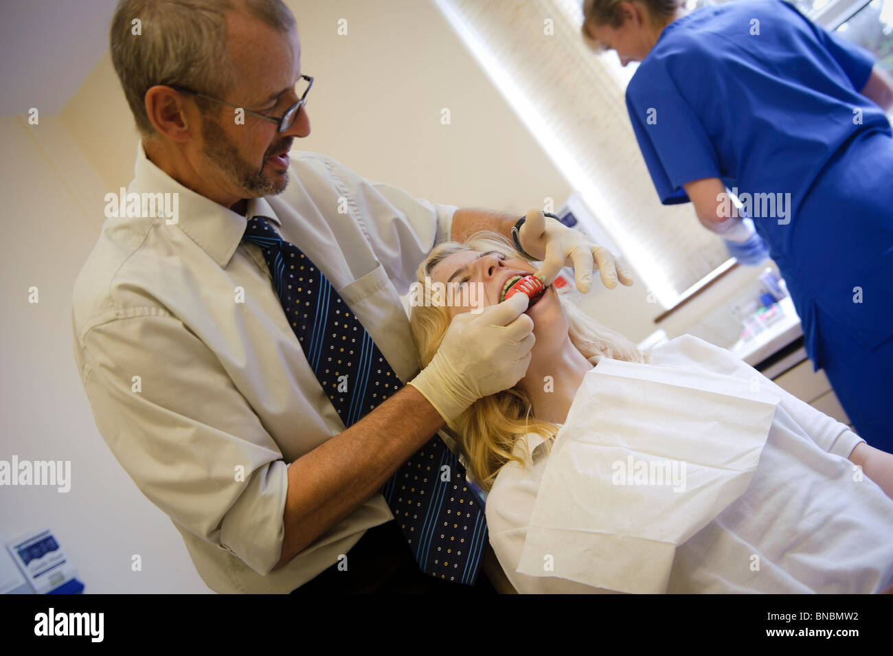 Ein National Health Service Kieferorthopäden unter einer Besetzung von einer Teenagerin Zähne, UK Stockfoto