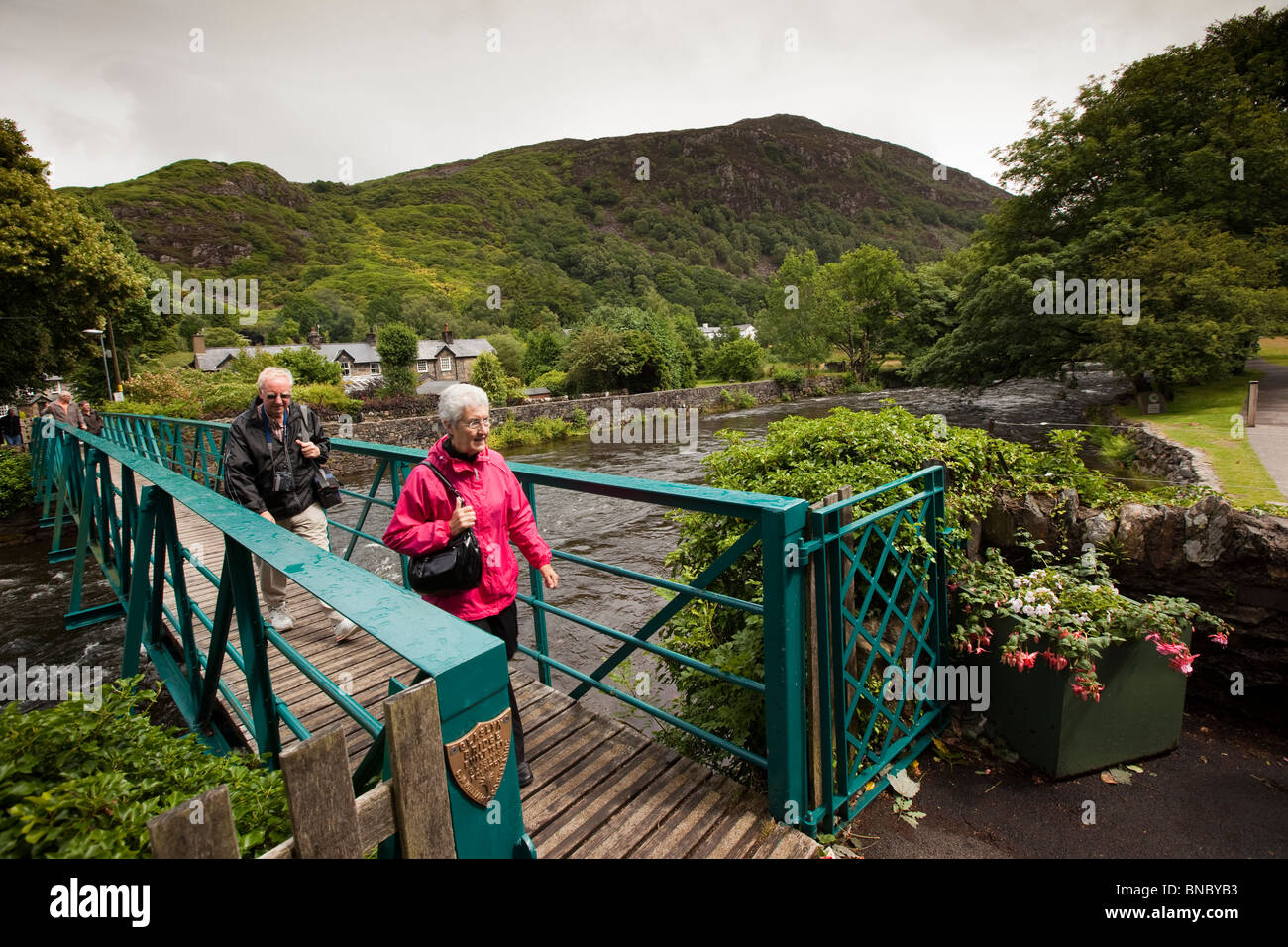 Großbritannien, Wales, Snowdonia, Beddgelert, zwei Wanderer Afon Glaslyn Eisenbrücke überqueren Stockfoto