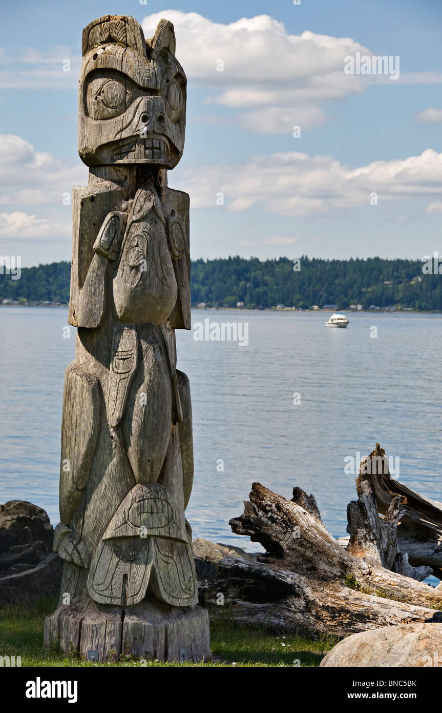 Ein Totempfahl steht auf der Küste von Blake-Insel mit schönen Puget Sound im Hintergrund. Stockfoto