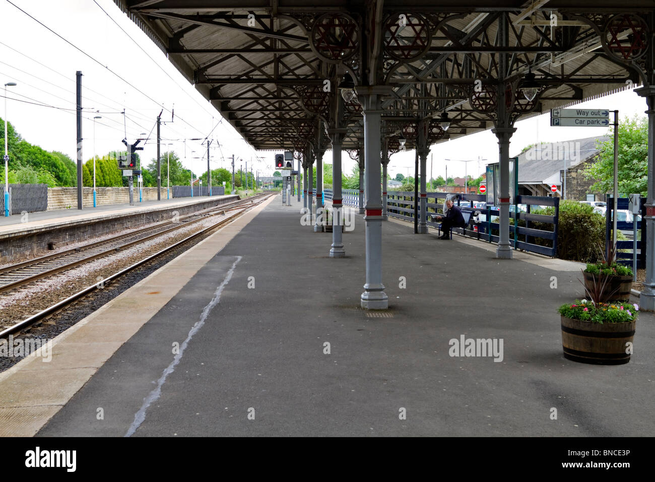 Morpeth Bahnhof. Ein Passagier sitzt auf einer Bank auf der leeren Plattform einen Zug warten. Stockfoto