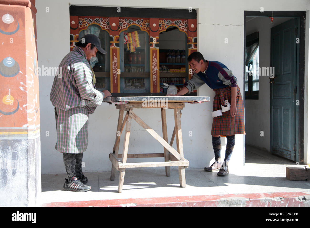 Zwei Männer spielen die traditionelle Brettspiel Carrom in den Straßen von Paro, Bhutan. Stockfoto