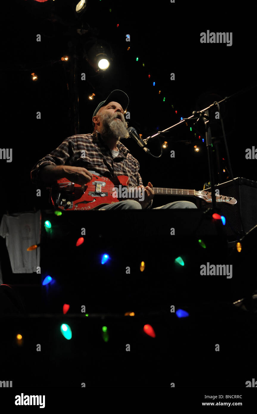 Bluesman Seasick Steve auf der Bühne mit seiner roten Boogie-Gitarre, umgeben von bunten Lichtern Stockfoto