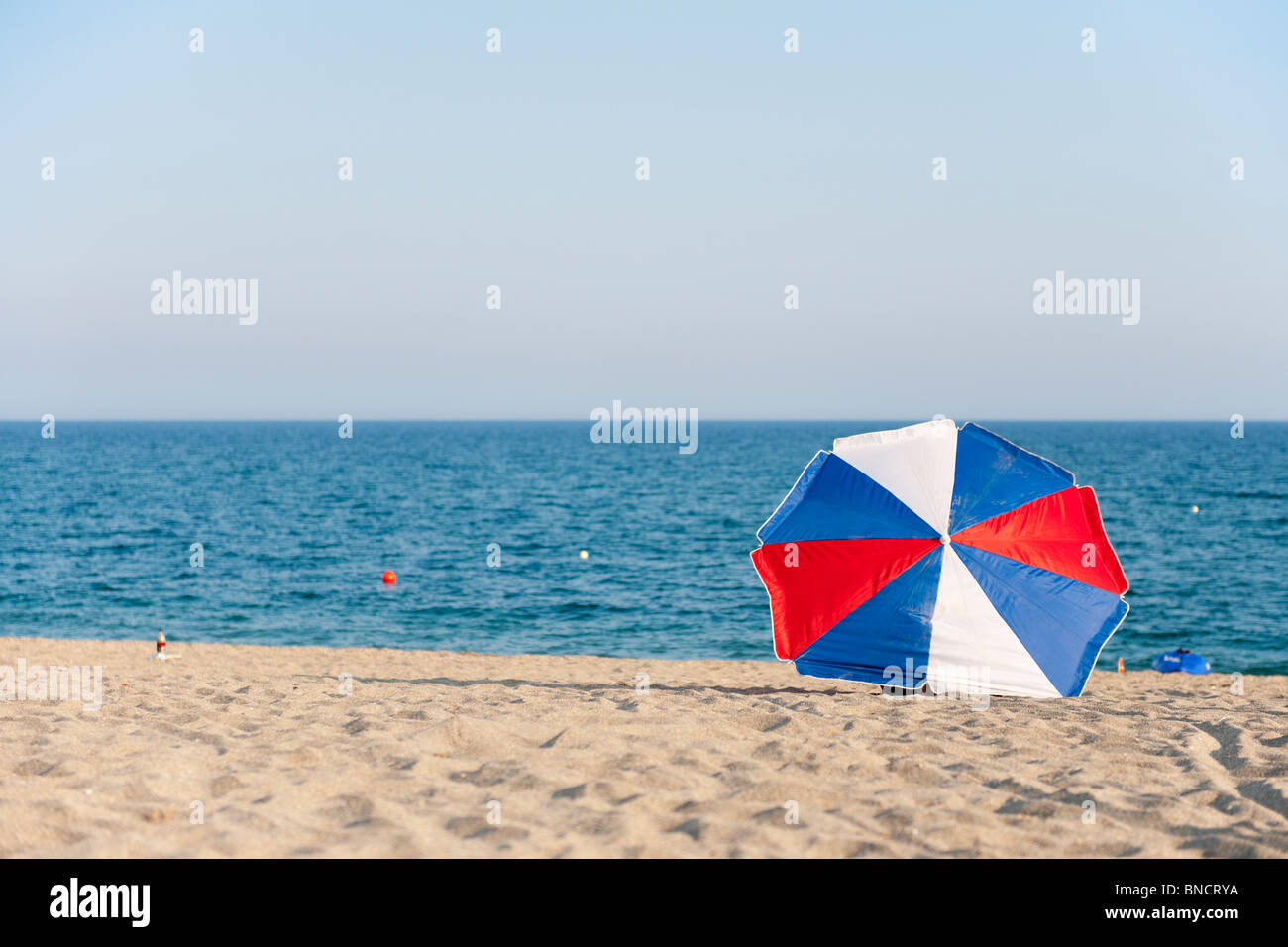 Rot weiß und blau Sonnenschirm am Strand Stockfoto