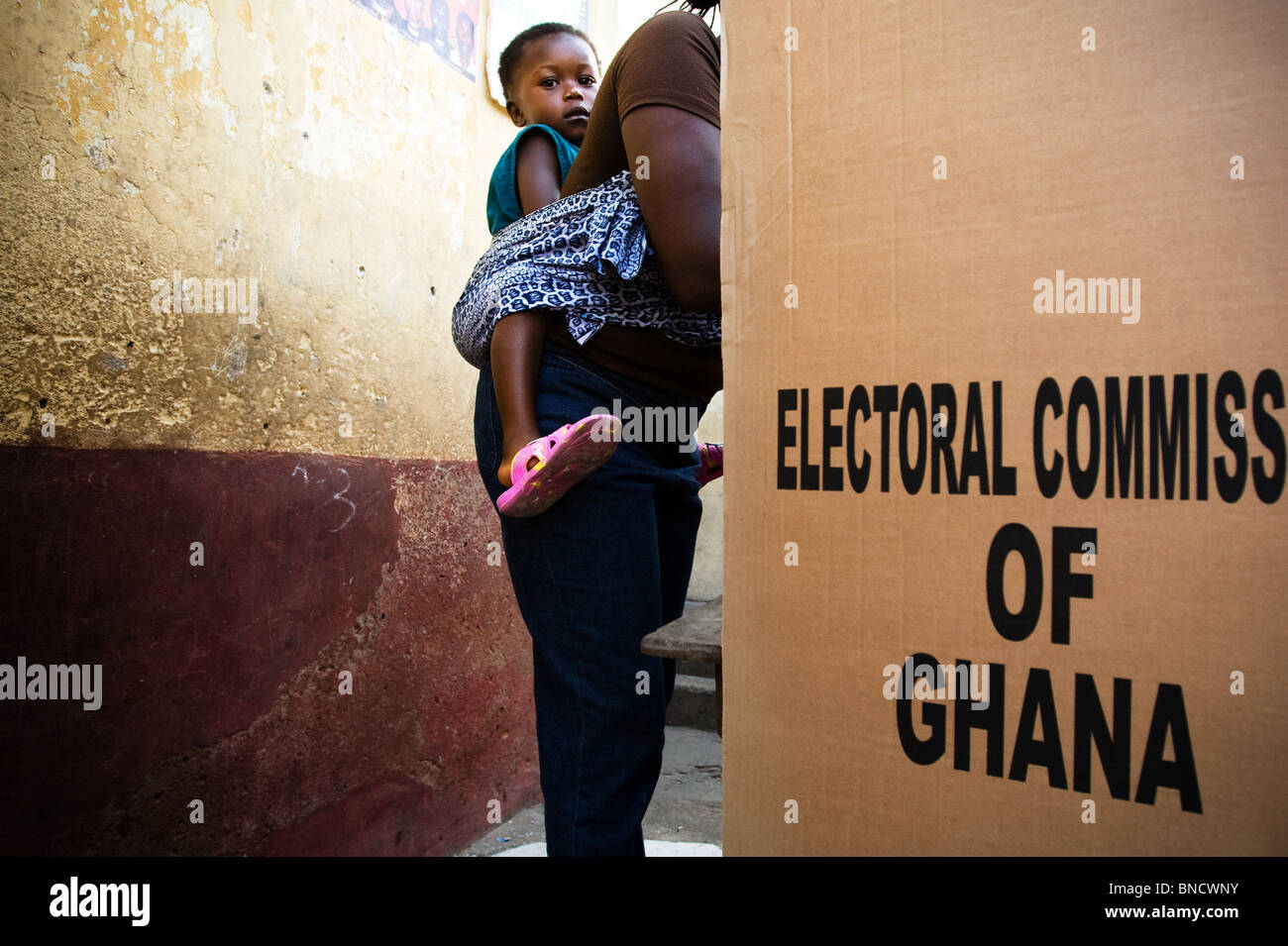 Eine Frau mit ihrem Kind auf dem Rücken Stimmen in einer Kabine während Präsidentschafts- und Parlamentswahlen in Accra, Ghana Stockfoto