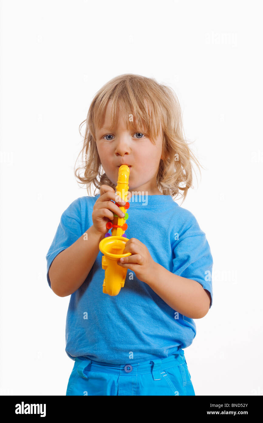 Junge mit langen blonden Haaren spielen mit Spielzeug-Saxophon Stockfoto