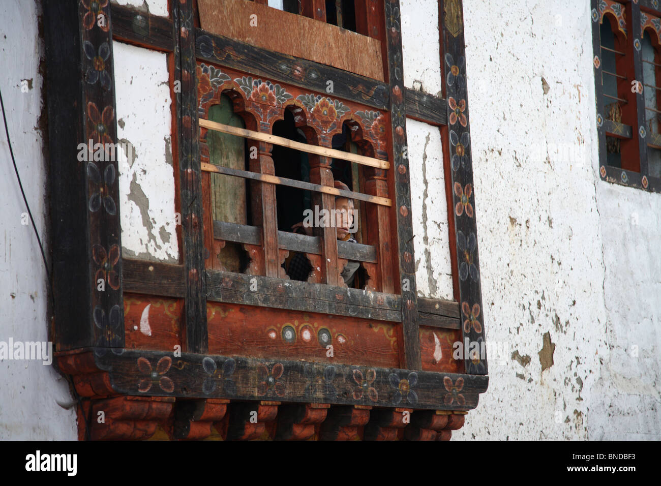 Ein Gesicht-peering-Out aus dem Fenster eines Wohnhauses in Paro, Bhutan. Stockfoto