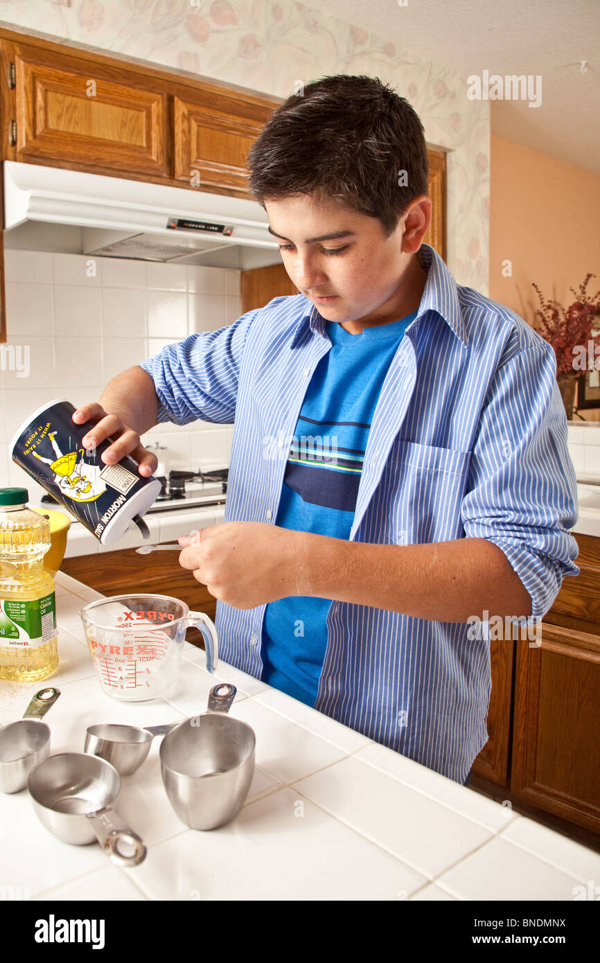 Hispanic Teenager trug ein blaues Hemd messen Zutaten kochen. Herr © Myrleen Pearson Stockfoto