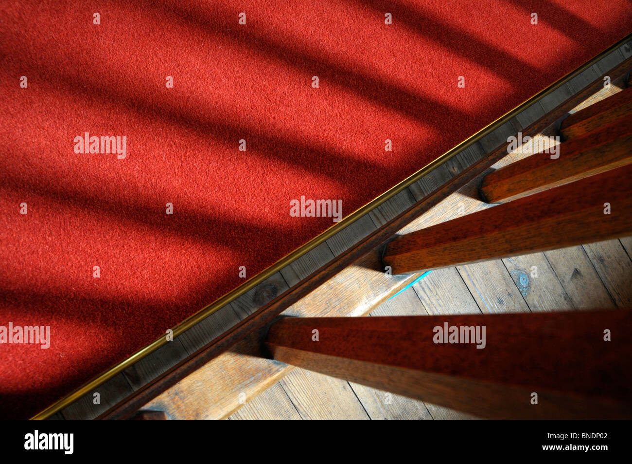 Auszug aus einem roten Teppich und hölzerne Geländer und ihre Schatten. Stockfoto