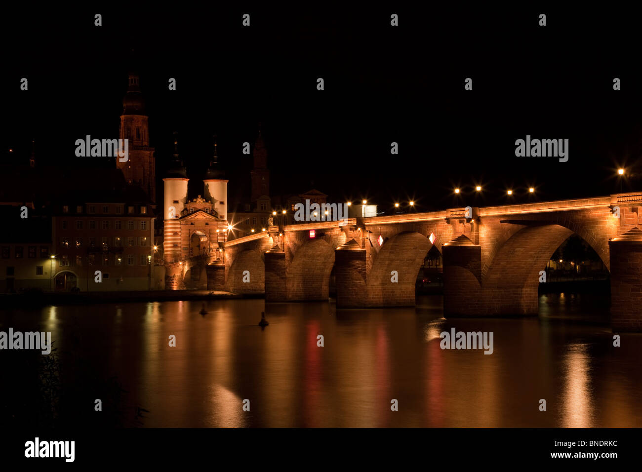 Die berühmten historischen Heidelberger Brücke beleuchtet in der Nacht in Bayern Deutschland weich fließenden Neckar mit Reflexionen der Brücke und warmen Lichter Stockfoto
