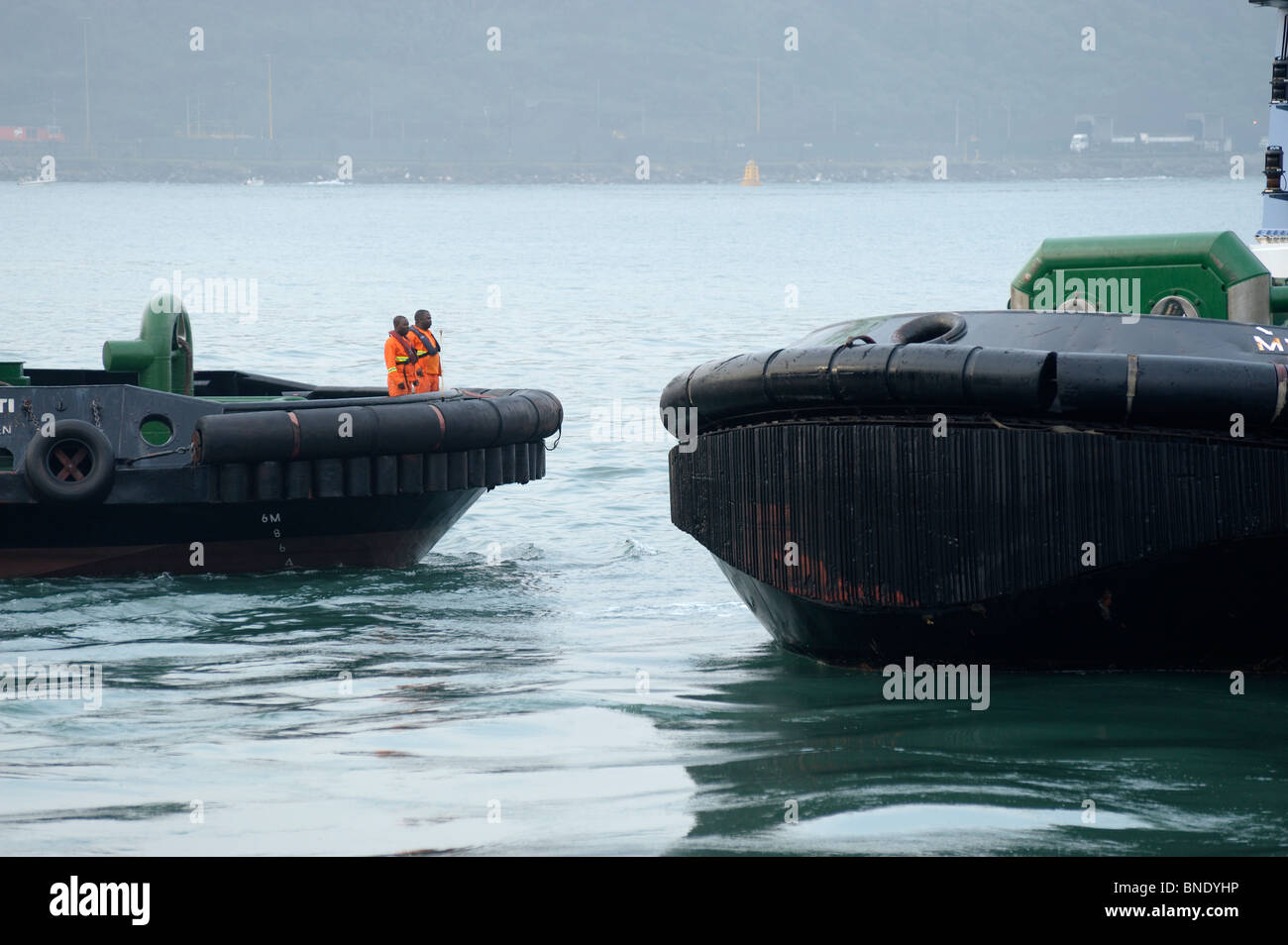 Bunt gekleidet Hafenarbeiter an Bord ein Schlepper im Hafen von Durban, Durban, Kwazulu Natal, Südafrika Stockfoto