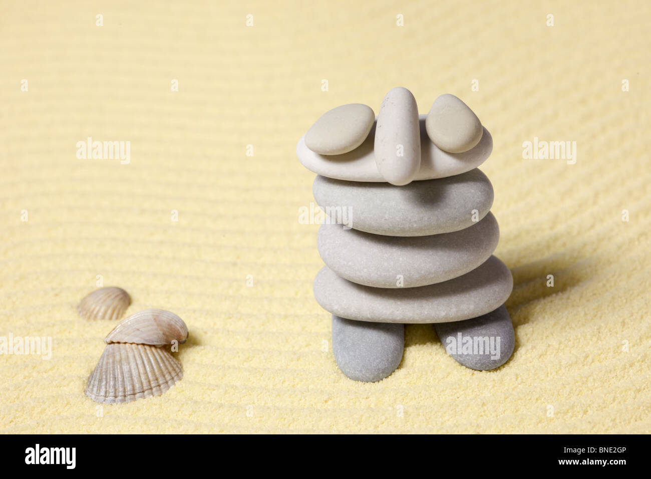 Lustige Figur des Menschen aus dem Kiesel gegen Strandsand Stockfoto