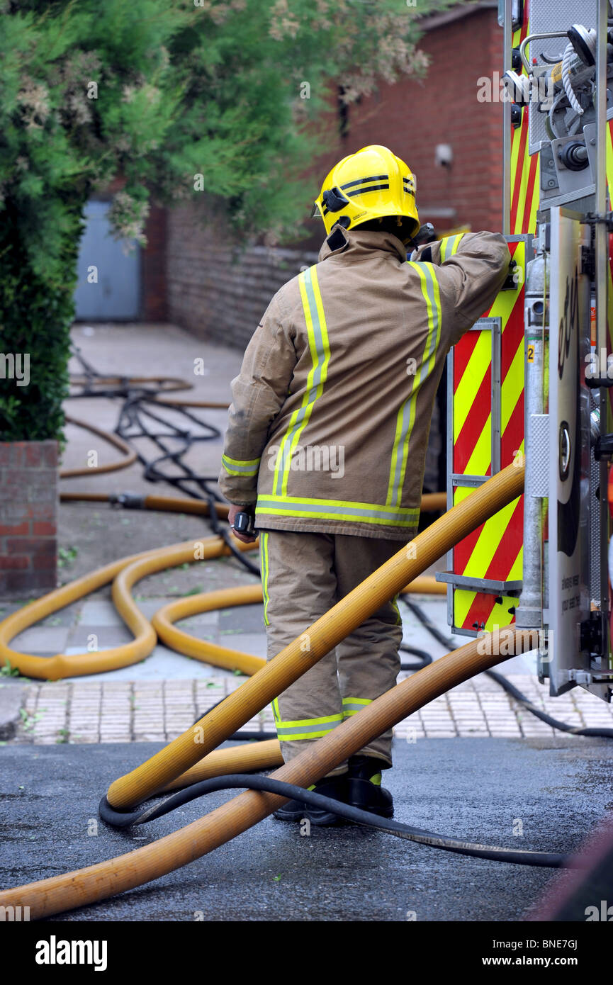 Feuerwehrmann steht stützte sich auf das Feuerwehrauto an der Szene eines Feuers in Brighton, Sussex, Großbritannien Stockfoto