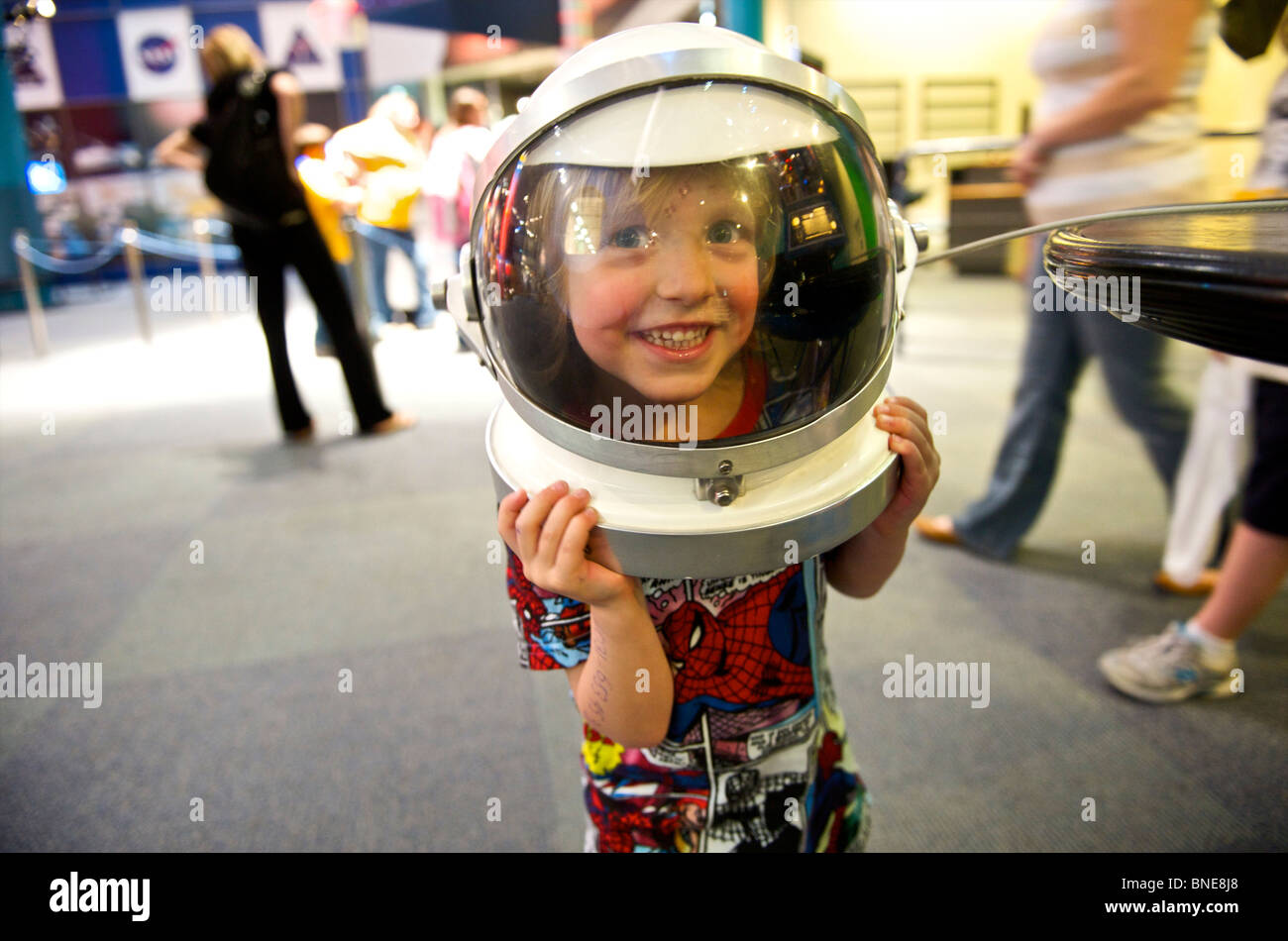 Drei Jahre alter Junge versucht eine sehr schwere Astronauten Helm im Raumfahrtzentrum, Houston, Texas, USA Stockfoto