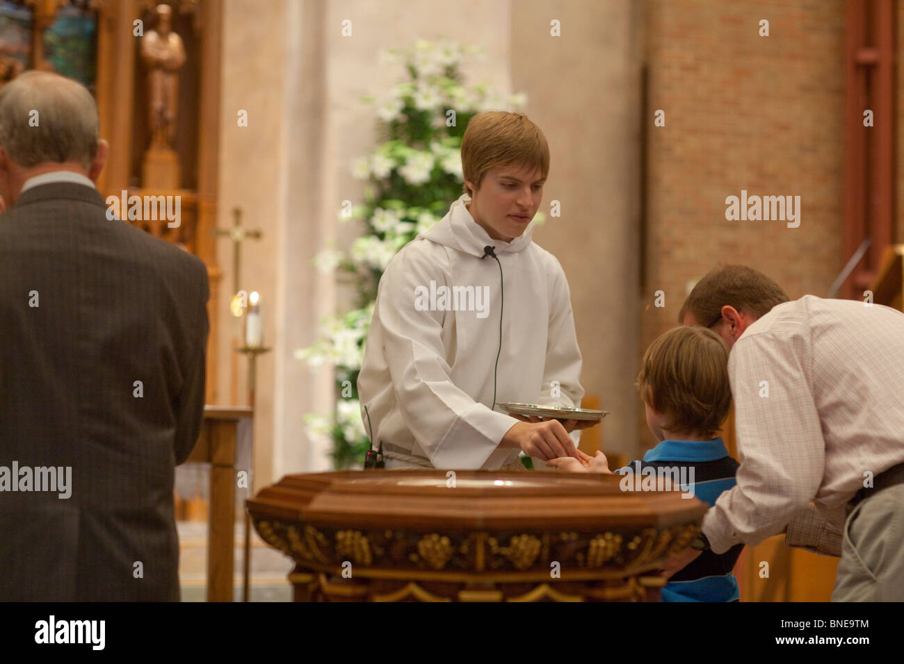 Junge männliche Unterstützung Minister verleiht junge Hostie während Ostern Sonntagsgottesdienst am St.-Martins Kirche Stockfoto