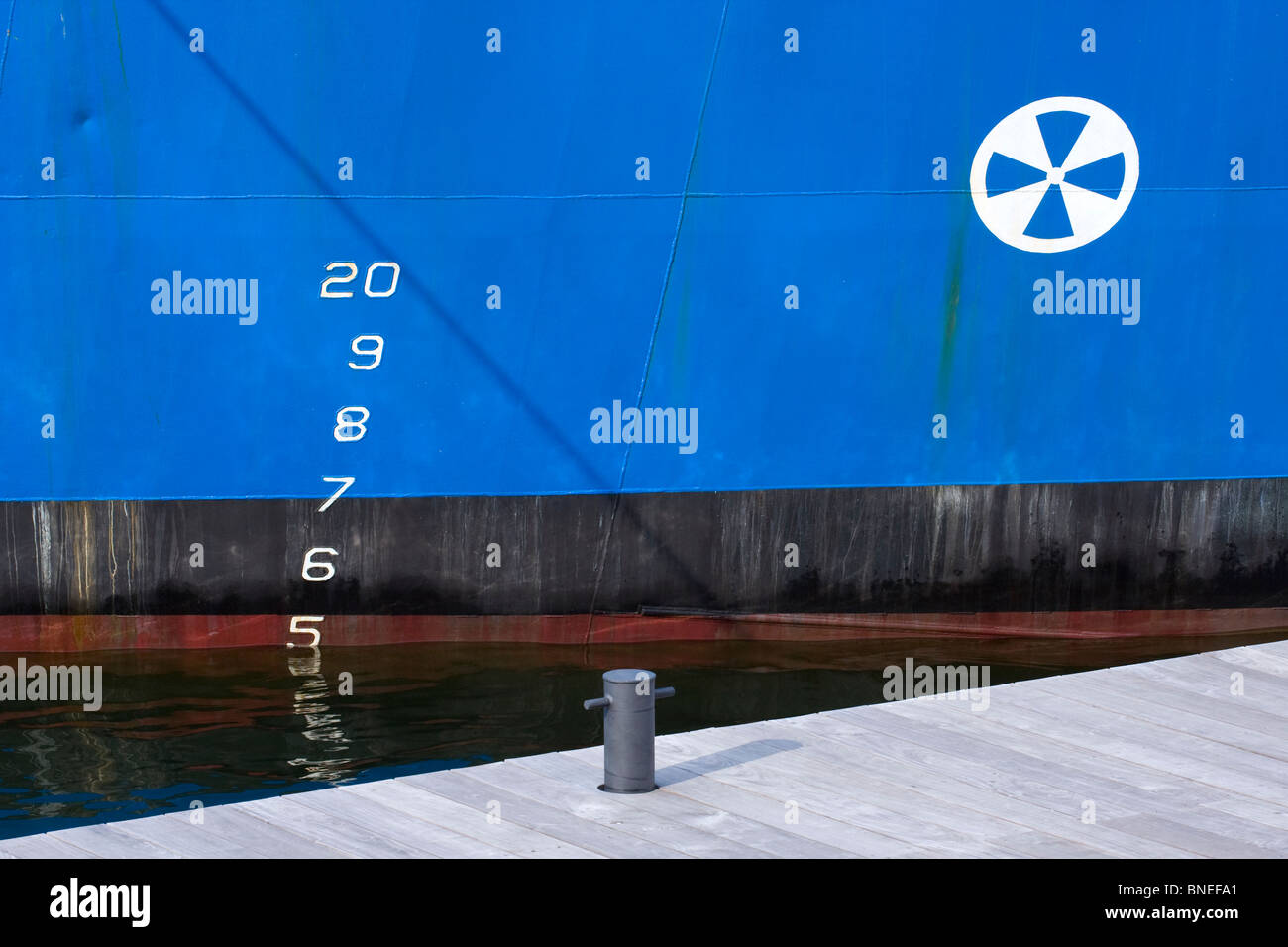 Stahl Rumpf des blauen Boot im Wasser mit Entwurf Markierungen und Pier Klampe am Dock. Stockfoto
