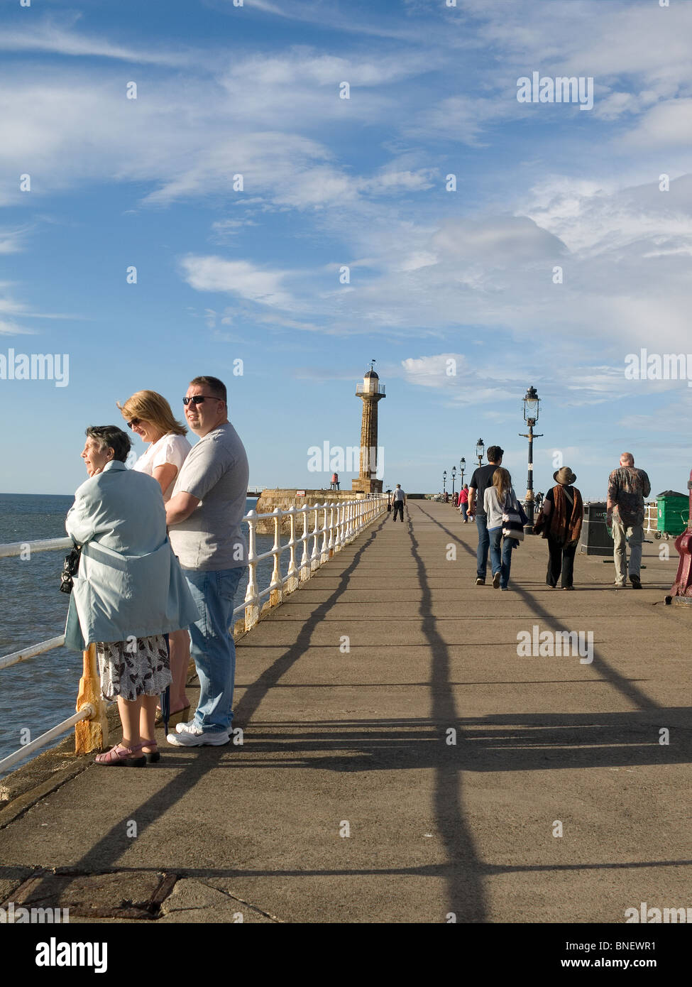 Menschen genießen die Abendsonne auf Whitby West pier Stockfoto